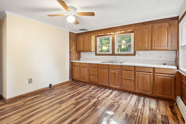 20 Mack Rd, Middlefield, CT 06455 - kitchen featuring brown cabinetry, a baseboard heating unit, wood finished floors, decorative backsplash, and light countertops