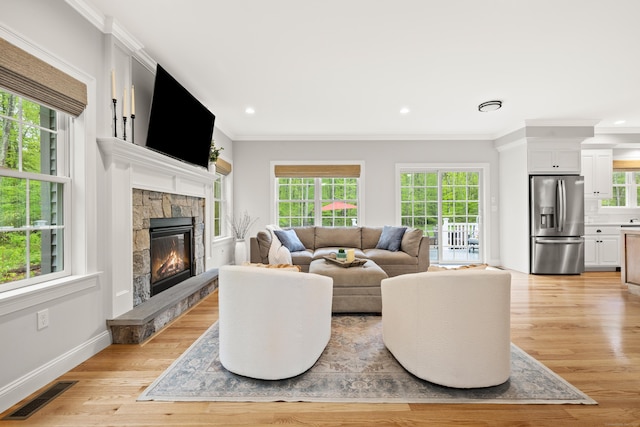 261 W St, Hebron, CT 06248 - living area with plenty of natural light, a stone fireplace, light wood finished floors, ornamental molding, and recessed lighting