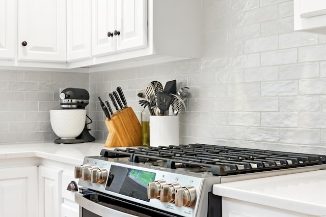261 W St, Hebron, CT 06248 - kitchen view of stainless steel gas range, decorative backsplash, white cabinetry, and light countertops