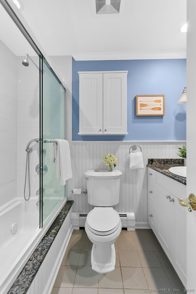 20 Aspen Mill Rd, Ridgefield, CT 06877 - full bathroom featuring baseboard heating, tiled shower / bath combo, wainscoting, vanity, and tile patterned floors