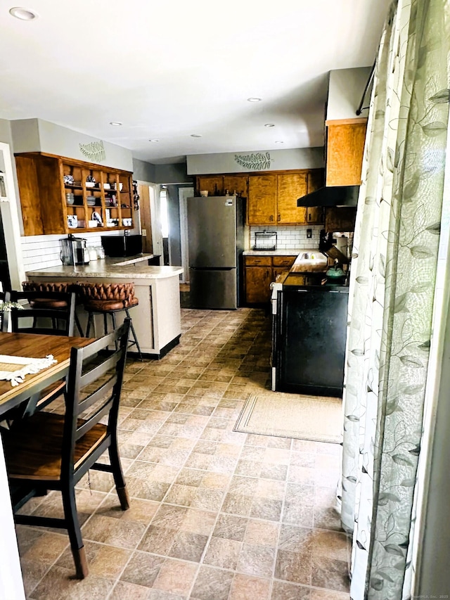 78 French St, Bristol, CT 06010 - kitchen with freestanding refrigerator, backsplash, a peninsula, premium range hood, and brown cabinetry