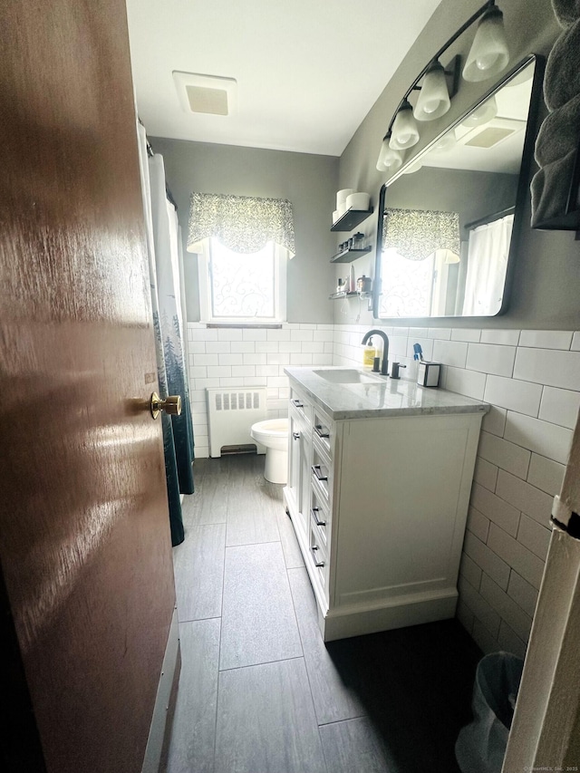 78 French St, Bristol, CT 06010 - bathroom featuring tile walls, radiator, vanity, and a wainscoted wall