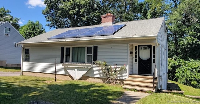 4 Clyne Ave, Waterbury, CT 06705 - view of front of home with a front yard, roof mounted solar panels, a chimney, and entry steps