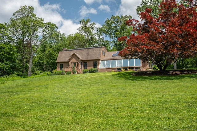 79 Ben Whitney Ln, Bridgewater, CT 06752 - view of front of home featuring a front yard, a chimney, a sunroom, and roof mounted solar panels