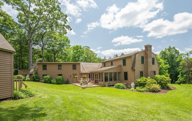 79 Ben Whitney Ln, Bridgewater, CT 06752 - back of property featuring a sunroom, a chimney, a patio, and a lawn