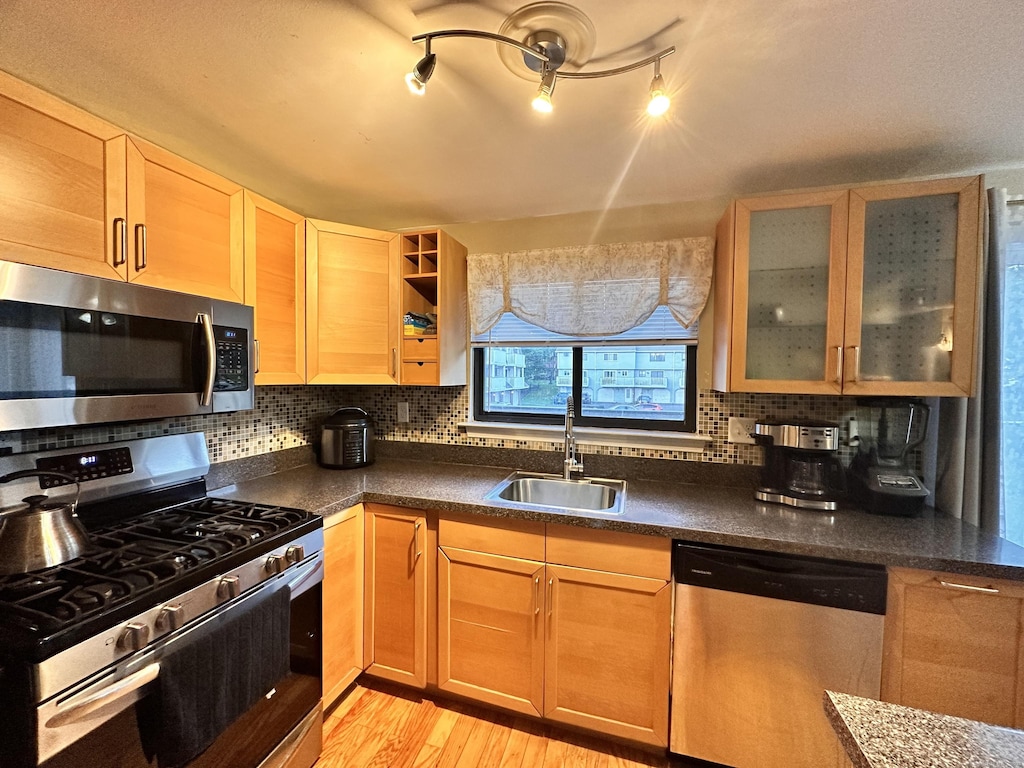 74 Churchill Dr Unit 74, Newington, CT 06111 - kitchen featuring stainless steel appliances, dark countertops, decorative backsplash, and light wood-type flooring