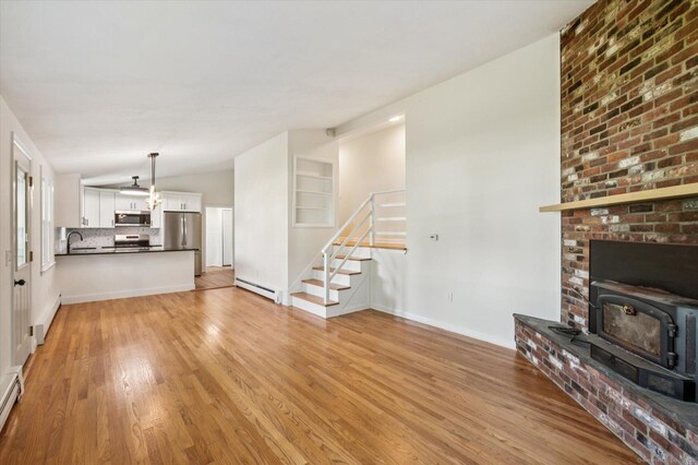 75 Atwood Hts, Thomaston, CT 06787 - unfurnished living room featuring a wood stove, baseboard heating, lofted ceiling, light wood-type flooring, and stairway
