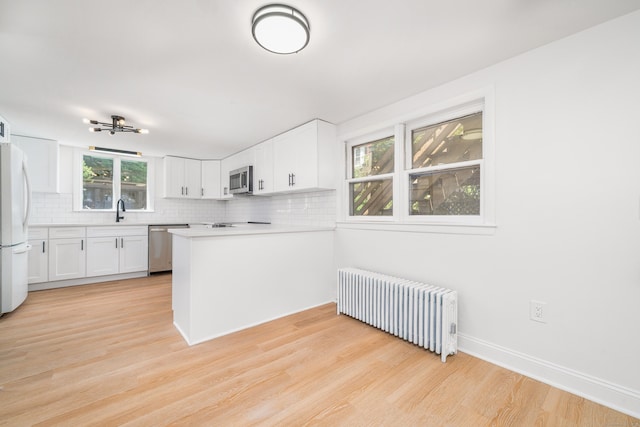 105 High St, Sprague, CT 06330 - kitchen featuring radiator, appliances with stainless steel finishes, decorative backsplash, light wood-style flooring, and white cabinets