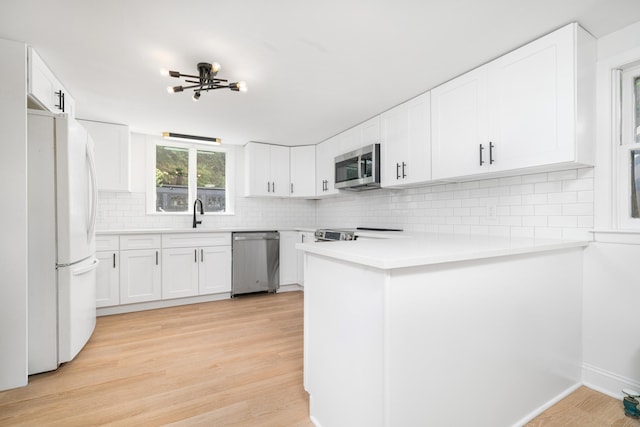 105 High St, Sprague, CT 06330 - kitchen featuring stainless steel appliances, a peninsula, decorative backsplash, light wood finished floors, and light countertops