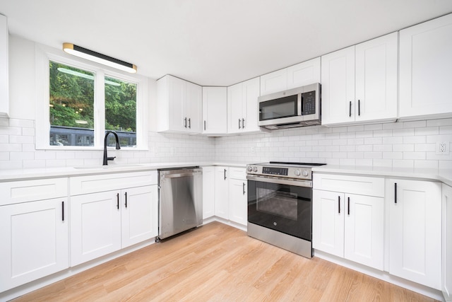 105 High St, Sprague, CT 06330 - kitchen featuring appliances with stainless steel finishes, light countertops, decorative backsplash, and light wood-type flooring