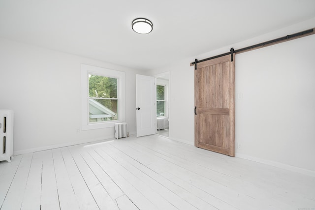 105 High St, Sprague, CT 06330 - spare room with radiator heating unit, a barn door, and light wood-style flooring