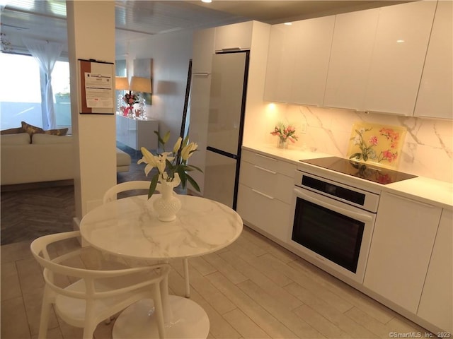 350 Grovers Ave Unit 11A, Bridgeport, CT 06605 - kitchen with oven, freestanding refrigerator, black electric cooktop, white cabinets, and modern cabinets
