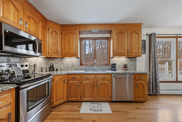 10 Heritage Dr, Prospect, CT 06712 - kitchen featuring appliances with stainless steel finishes, light wood finished floors, a textured ceiling, brown cabinets, and light stone countertops