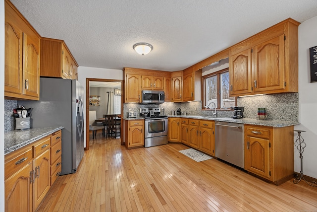10 Heritage Dr, Prospect, CT 06712 - kitchen with appliances with stainless steel finishes, brown cabinetry, light wood-style floors, tasteful backsplash, and a textured ceiling
