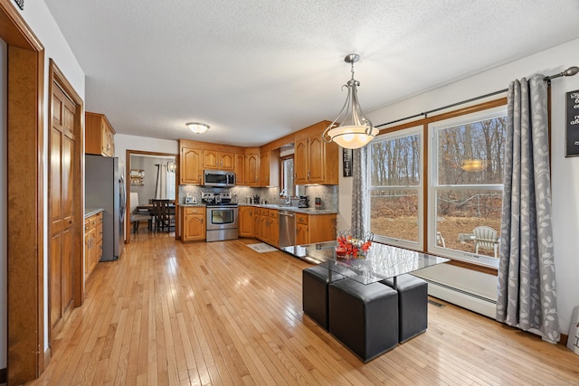 10 Heritage Dr, Prospect, CT 06712 - kitchen with stainless steel appliances, brown cabinetry, light wood-type flooring, and a textured ceiling