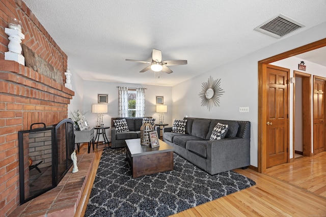 10 Heritage Dr, Prospect, CT 06712 - living room featuring a ceiling fan, wood finished floors, a brick fireplace, and a textured ceiling