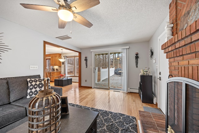 10 Heritage Dr, Prospect, CT 06712 - living area featuring baseboard heating, a textured ceiling, light wood-style flooring, a fireplace, and a ceiling fan