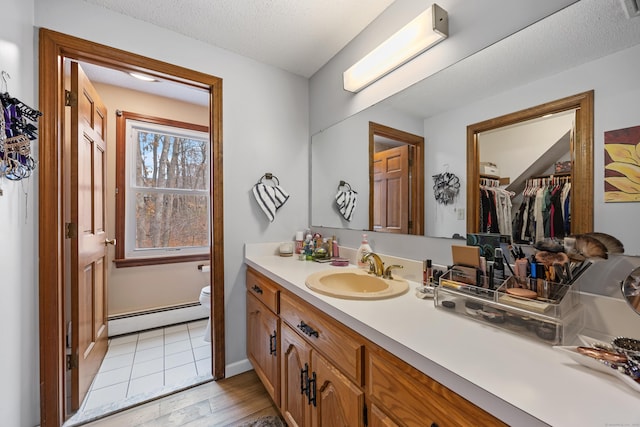 10 Heritage Dr, Prospect, CT 06712 - bathroom featuring a baseboard radiator, vanity, a walk in closet, wood finished floors, and a textured ceiling