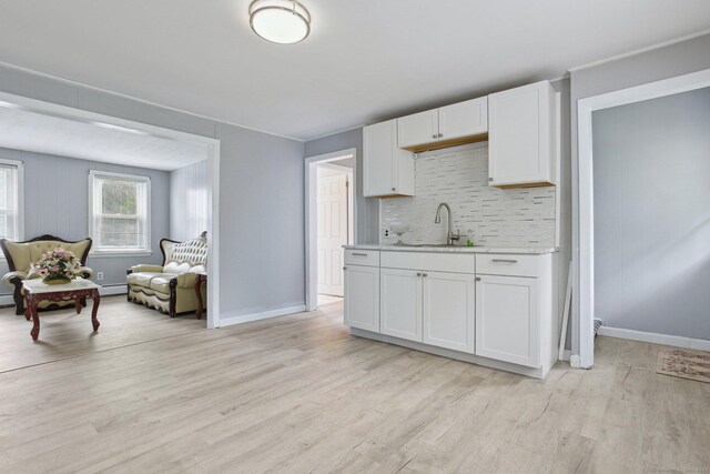 8 3rd St, Norwich, CT 06360 - kitchen featuring light countertops, light wood-style flooring, backsplash, white cabinets, and open floor plan