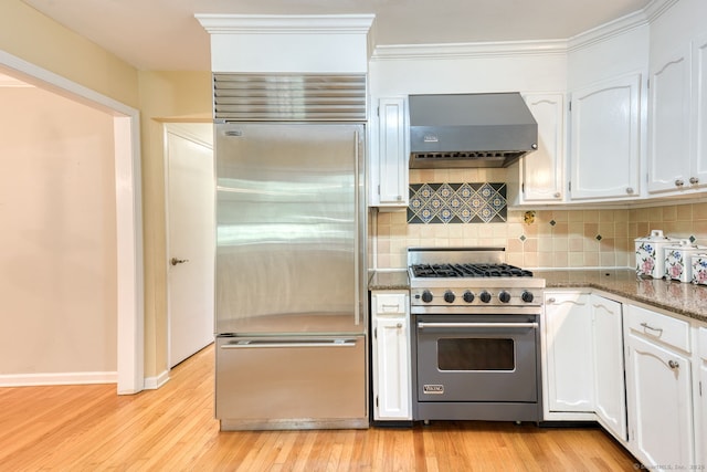 20 Copper Hill Dr Unit 20, Guilford, CT 06437 - kitchen featuring premium appliances, wall chimney range hood, white cabinets, tasteful backsplash, and ornamental molding