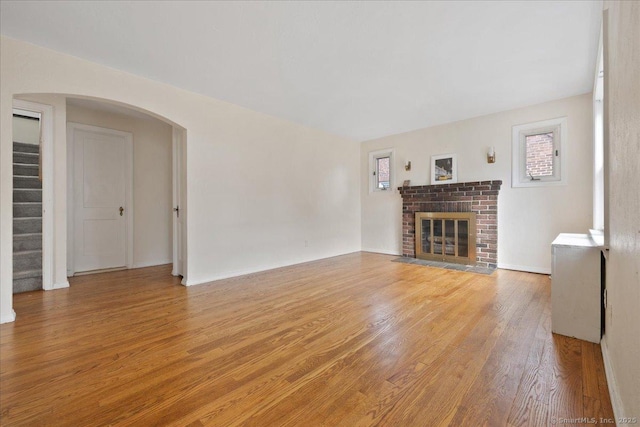 30 Cedar Crest Pl, Norwalk, CT 06854 - unfurnished living room with light wood finished floors, stairway, a brick fireplace, and arched walkways