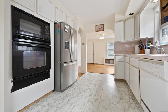 30 Cedar Crest Pl, Norwalk, CT 06854 - kitchen featuring black appliances, radiator, white cabinets, light countertops, and light marble finish flooring