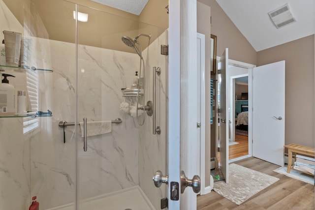 full bath with ensuite bathroom, a marble finish shower, wood finished floors, vaulted ceiling, and a baseboard heating unit