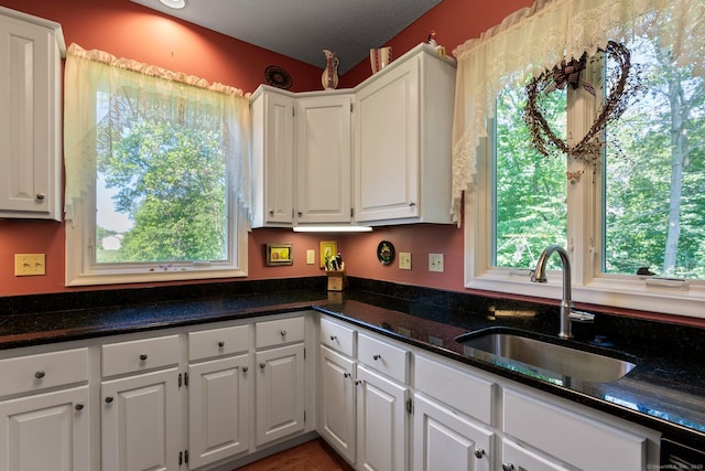 kitchen featuring white cabinetry and dark stone counters