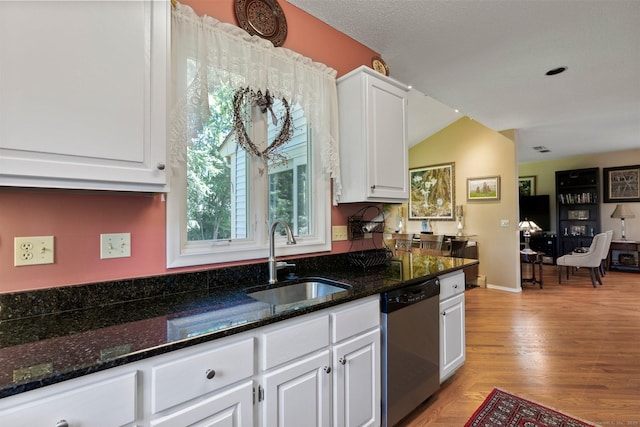 kitchen with stainless steel dishwasher, white cabinetry, light wood-style floors, and dark stone counters
