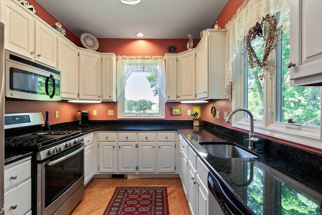kitchen with appliances with stainless steel finishes, dark stone counters, white cabinetry, a textured ceiling, and recessed lighting