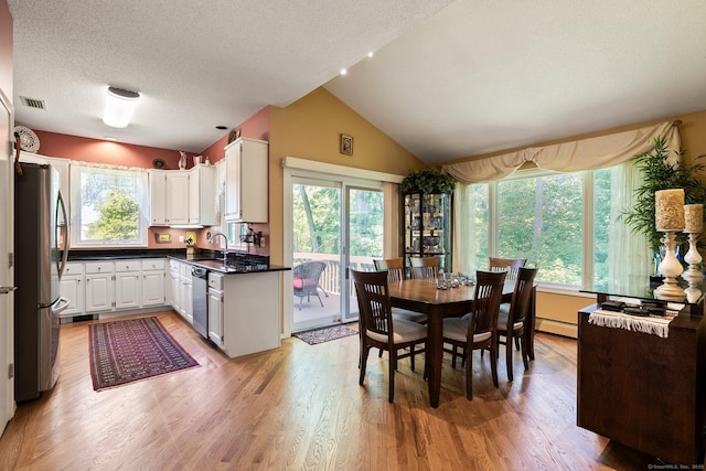 dining space with healthy amount of natural light, light wood-type flooring, lofted ceiling, a textured ceiling, and baseboard heating