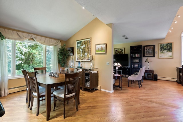 dining space with lofted ceiling, a baseboard heating unit, and light wood finished floors