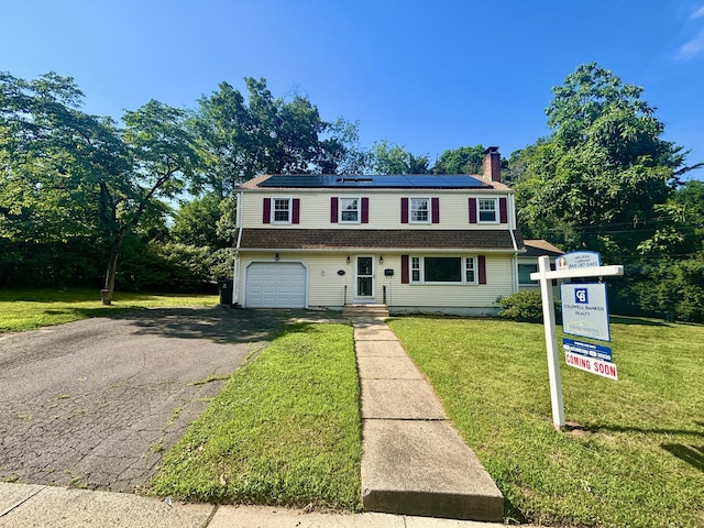 36 Westmoreland Dr, West Hartford, CT 06117 - view of front facade featuring roof mounted solar panels, an attached garage, a chimney, asphalt driveway, and a front lawn