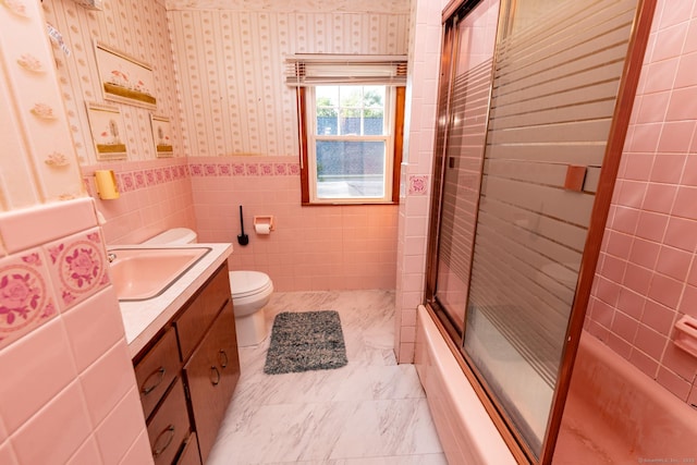 302 E Pasadena Pl, Bridgeport, CT 06610 - bathroom featuring wallpapered walls, vanity, combined bath / shower with glass door, wainscoting, and tile walls
