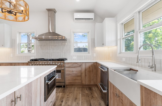 281 E Ave, Norwalk, CT 06850 - kitchen featuring wall chimney range hood, a wall mounted AC, stainless steel appliances, light wood-style floors, and healthy amount of natural light