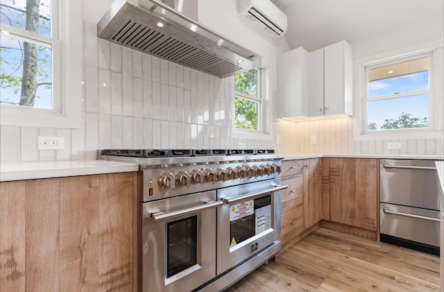 281 E Ave, Norwalk, CT 06850 - kitchen with wall chimney range hood, stainless steel appliances, a wall mounted air conditioner, and modern cabinets