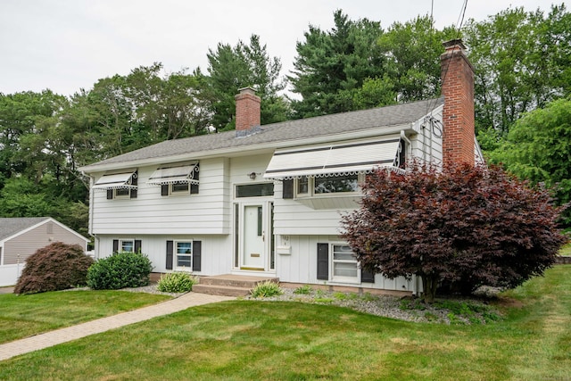 102 Herbert Dr, East Hartford, CT 06118 - raised ranch with a chimney, a front lawn, and view of wooded area