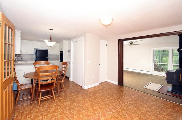 109 Pinnacle Rd, Ellington, CT 06029 - dining room featuring a wood stove, baseboard heating, a ceiling fan, and light flooring