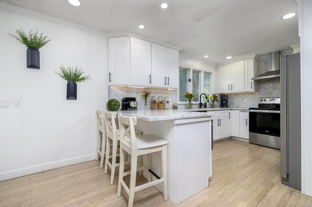 207 Hillcrest Rd, Bridgeport, CT 06606 - kitchen featuring appliances with stainless steel finishes, wall chimney range hood, a peninsula, backsplash, and white cabinetry