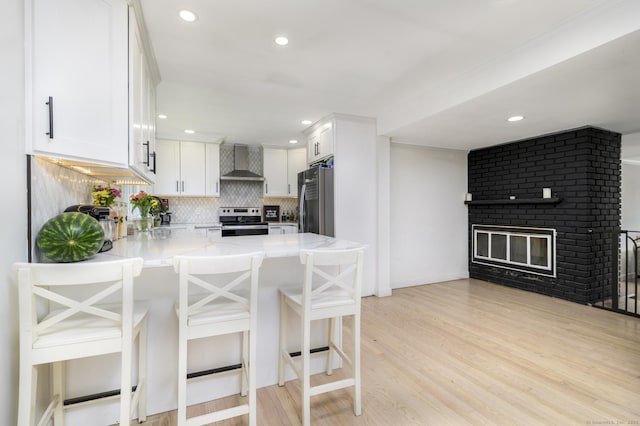 207 Hillcrest Rd, Bridgeport, CT 06606 - kitchen with appliances with stainless steel finishes, wall chimney exhaust hood, a peninsula, decorative backsplash, and white cabinetry