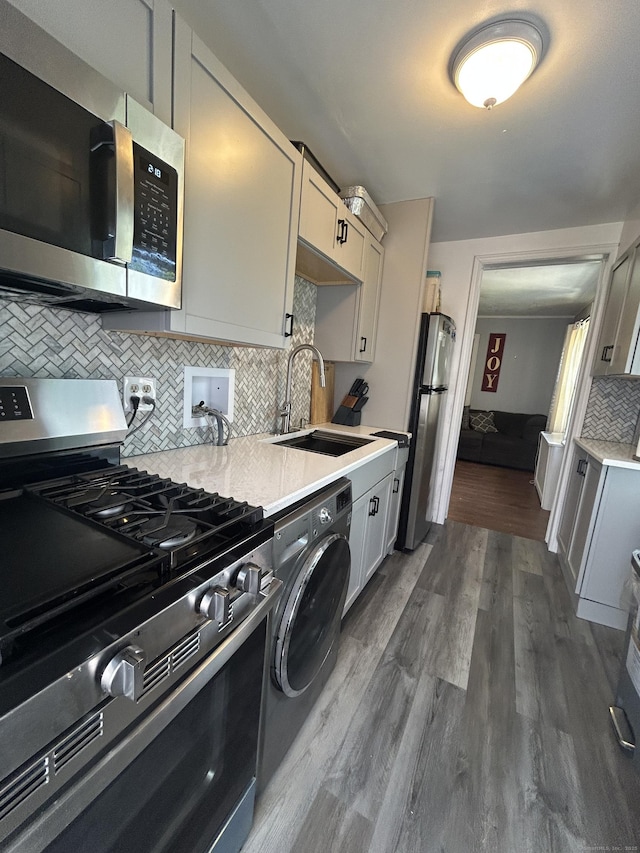 744 Canaan Rd Unit 23, Bridgeport, CT 06610 - kitchen featuring stainless steel appliances, washer / clothes dryer, light countertops, tasteful backsplash, and dark wood-type flooring