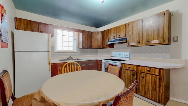 96 Davis Ave, Bridgeport, CT 06605 - kitchen with white appliances, under cabinet range hood, brown cabinetry, and light countertops