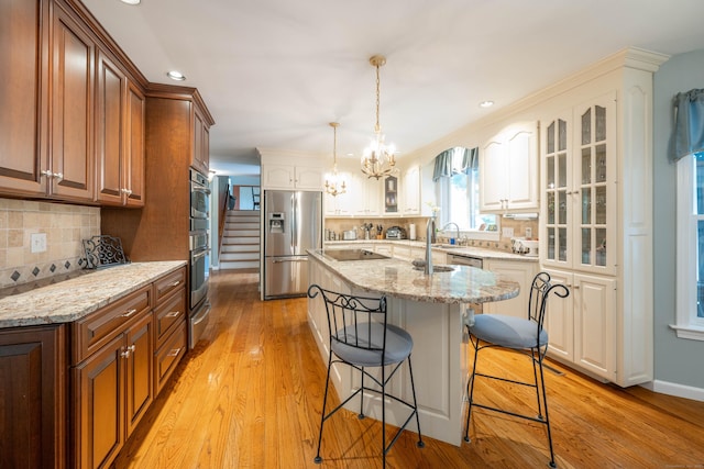 51 Wood Lot Ln, Southbury, CT 06488 - kitchen with stainless steel refrigerator with ice dispenser, a breakfast bar, glass insert cabinets, a center island with sink, and light stone countertops