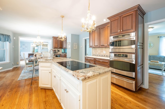 51 Wood Lot Ln, Southbury, CT 06488 - kitchen with a chandelier, black electric cooktop, a warming drawer, stainless steel double oven, and light wood-style flooring