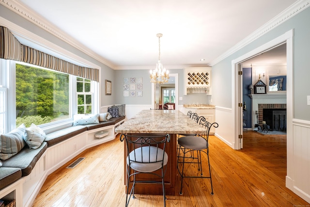 51 Wood Lot Ln, Southbury, CT 06488 - dining area with light wood-type flooring, a chandelier, wainscoting, ornamental molding, and a brick fireplace