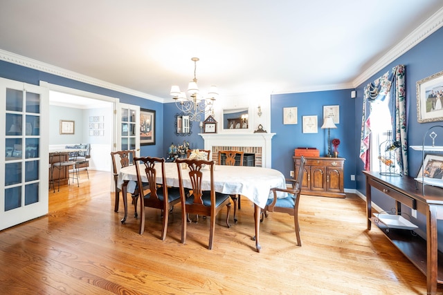 51 Wood Lot Ln, Southbury, CT 06488 - dining area with a chandelier, wood finished floors, ornamental molding, and a brick fireplace
