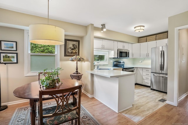 69 Ellsworth St Apt 101, Bridgeport, CT 06605 - kitchen with stainless steel appliances, a peninsula, light countertops, and light wood-type flooring