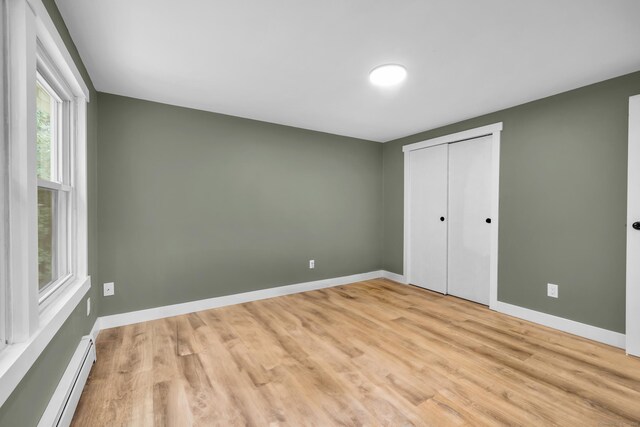 216 Old Monson Rd, Stafford, CT 06076 - unfurnished bedroom with baseboard heating, light wood-type flooring, and a closet