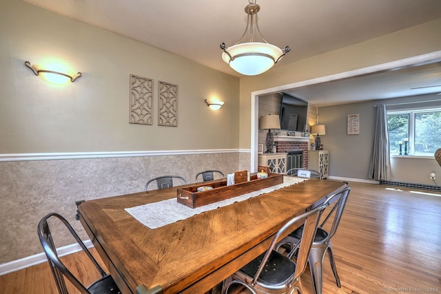 754 Riverside Dr, Orange, CT 06477 - dining area featuring a wainscoted wall, wood finished floors, and a brick fireplace