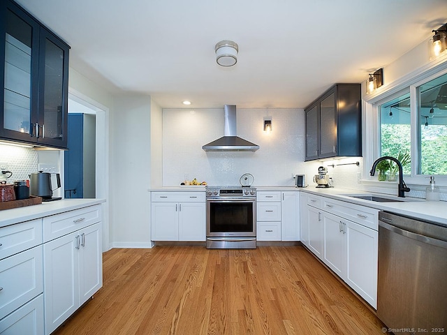 481 Gaylord Mountain Rd, Hamden, CT 06518 - kitchen featuring wall chimney range hood, appliances with stainless steel finishes, decorative backsplash, light wood finished floors, and glass insert cabinets